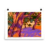 Two tree trunks are in the foreground with other trees in the distance, casting purple shade on the orange ground. Laura Hunt, artist.
